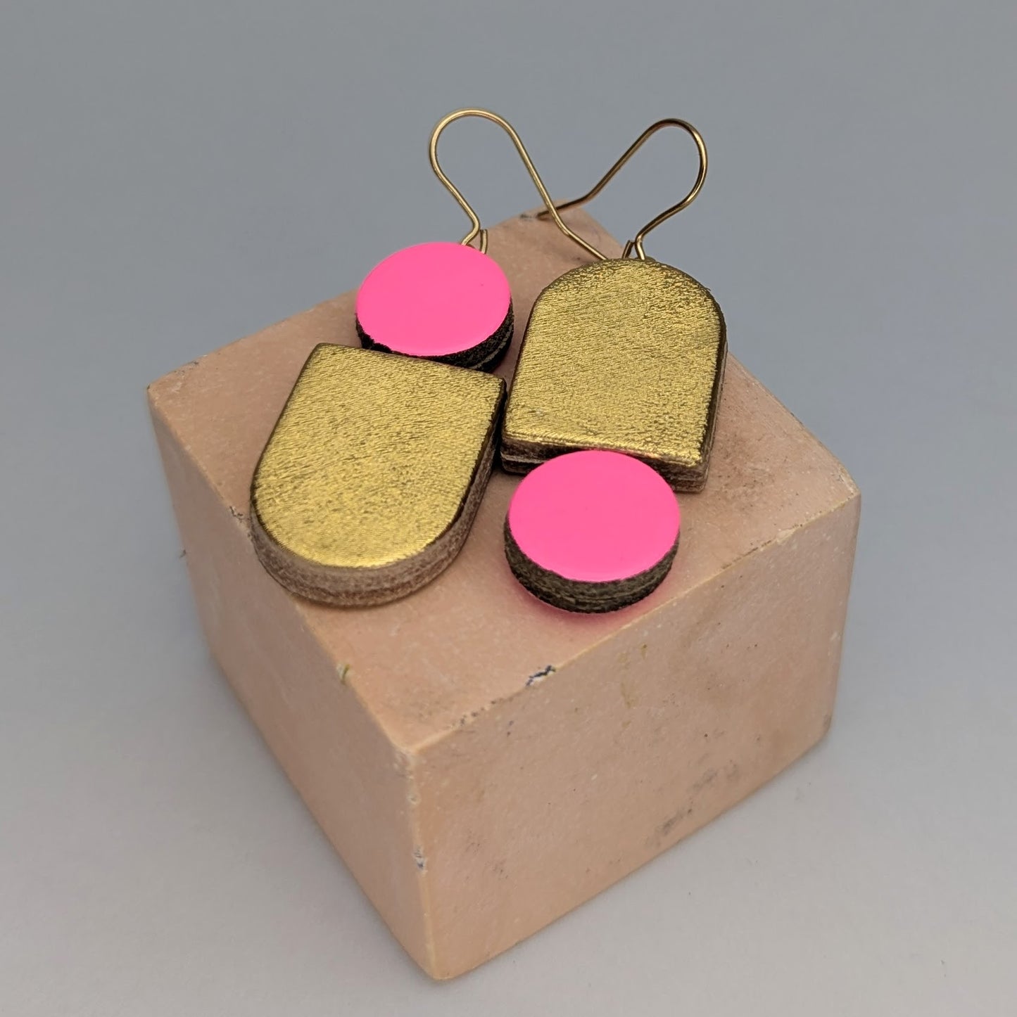 A pair of gold-plated earrings with fluoro pink and gold leather by Kay Morgan, Bristol.
